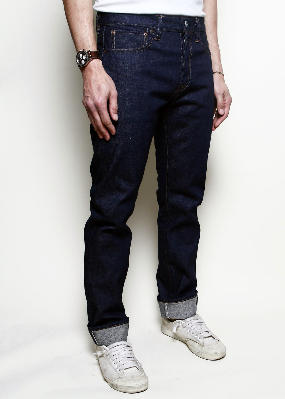 A three-quarter view of the Rogue Territory Stanton jean in raw indigo selvedge, showing the slim tapered leg, the back yoke and pockets, and the cuffed selvedge hem